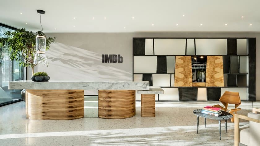 IMDb's reception today: the wordmark on a stone wall behind a marble desk